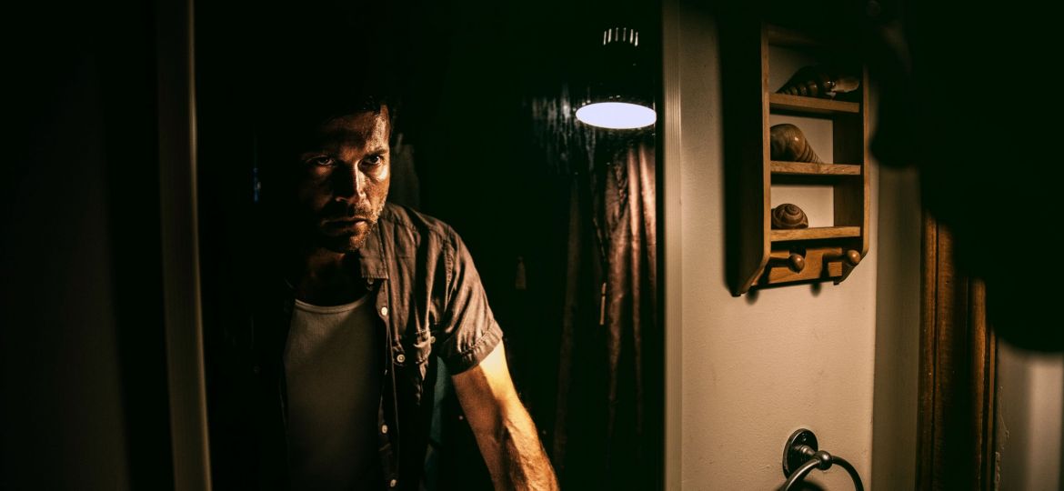 man standing in front of a mirror in the grips of a strong emotion